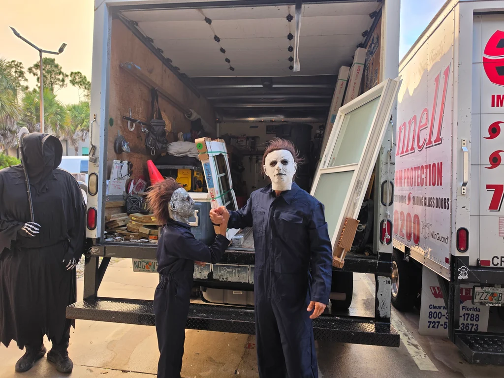 Halloween fun beside an O'Donnell truck, with two masked teammates posing together and a hooded teammate nearby.